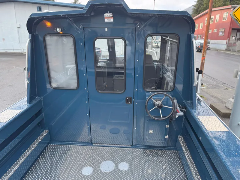 Slide: The Image of 2025 Hewescraft 220 Ocean Pro boat, blue exterior, rear view with steering wheel and cabin door. - 9