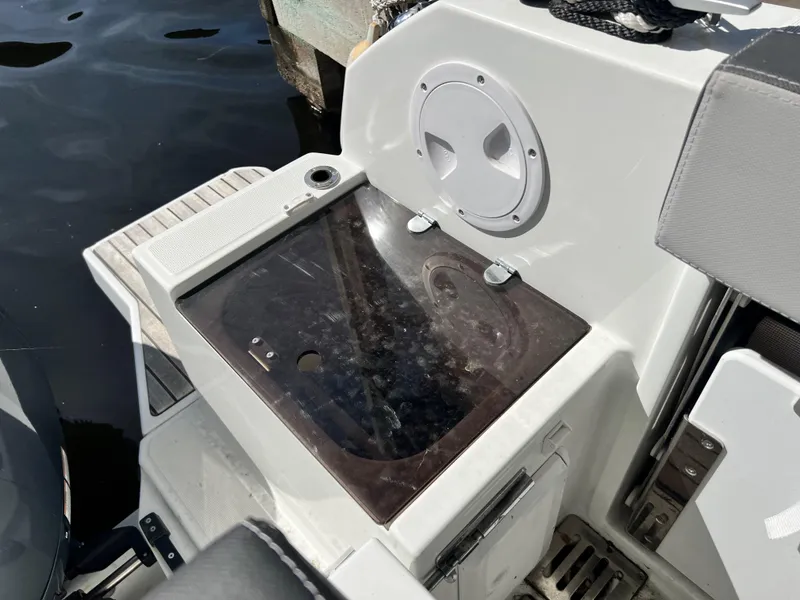 Slide: The Image of 2022 Jeanneau NC 895 Sport boat sink area with storage, docked by water. - 10