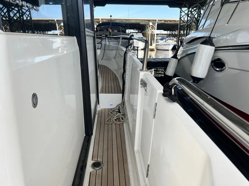 Slide: The Image of 2022 Jeanneau NC 895 Sport boat docked, showcasing sleek side deck and modern design. - 11