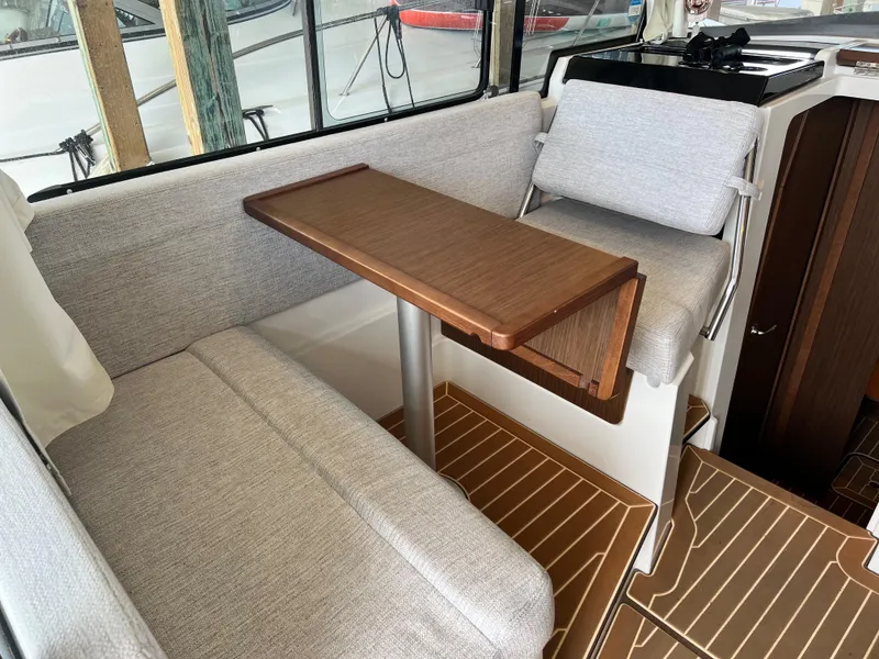 Slide: The Image of 2022 Jeanneau NC 895 Sport interior with seating and wooden table. - 18