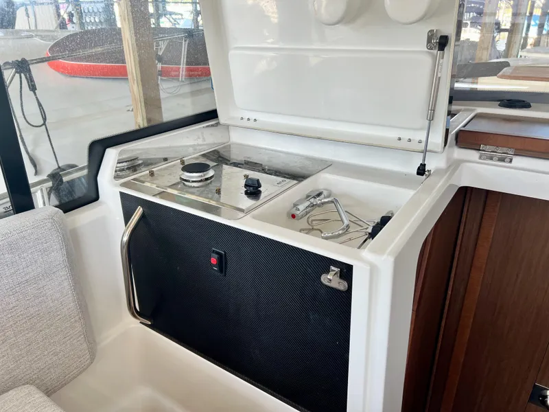 Slide: The Image of 2022 Jeanneau NC 895 Sport boat interior with compact kitchen area and stove. - 19