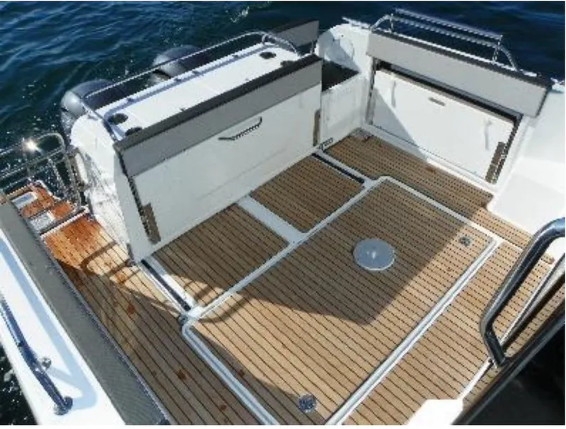 Slide: The Image of 2022 Jeanneau NC 895 Sport boat deck with wood finish and storage compartments. - 8