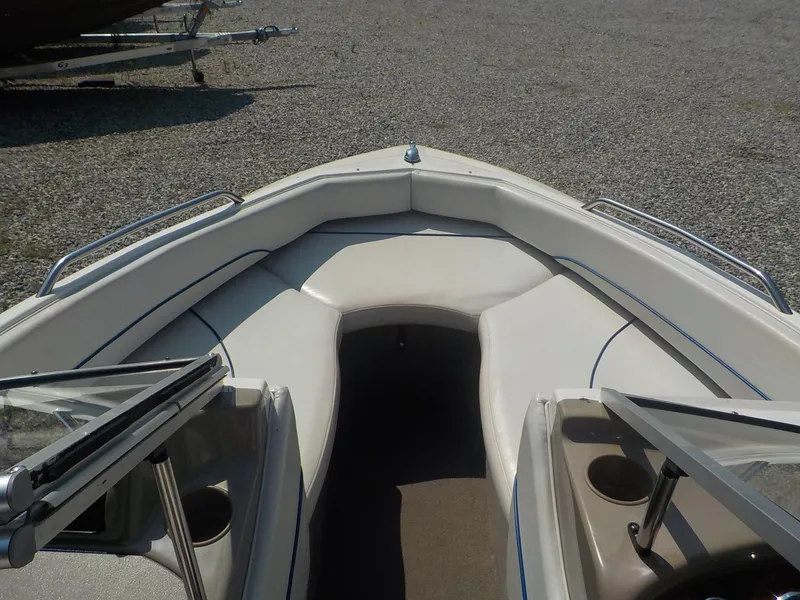 Slide: The Image of 2004 Bayliner 195 Classic boat interior with seating and windshield, parked on gravel. - 10