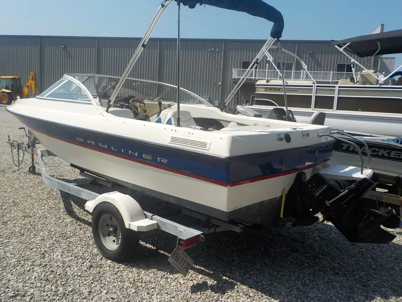 Slide: The Image of 2004 Bayliner 195 Classic boat on trailer, parked outdoors near a metal building. - 6
