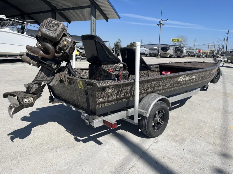 Slide: The Image of 2023 Pro-Drive SBX 1854 Stick Drive boat on trailer, camo design, outdoor setting. - 13