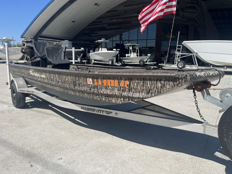 Slide: The Image of 2023 Pro-Drive SBX 1854 Stick Drive boat on trailer, American flag in background. - 8
