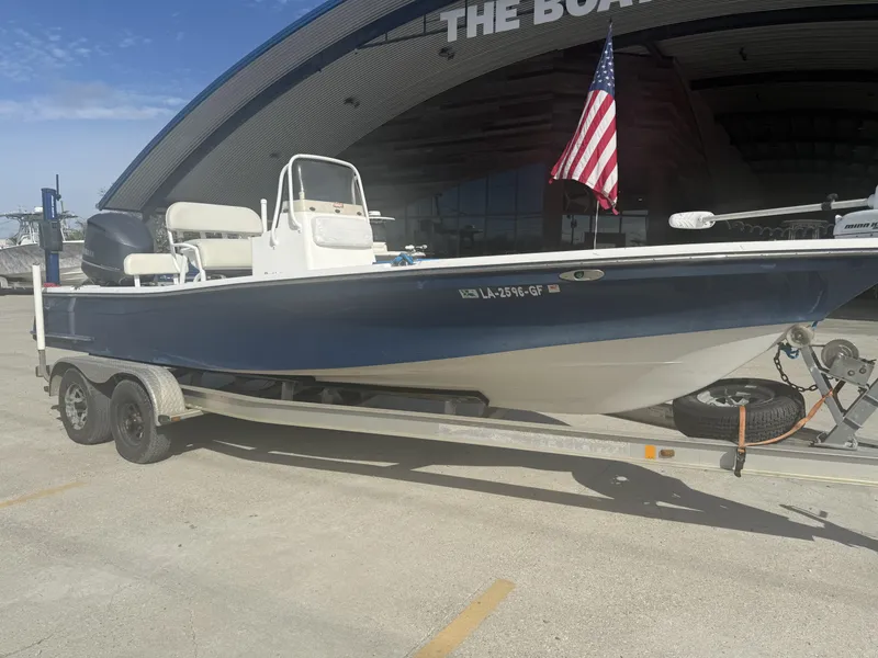 Slide: The Image of 2013 BlackJack 224 boat on trailer with American flag, parked outside a building. - 13