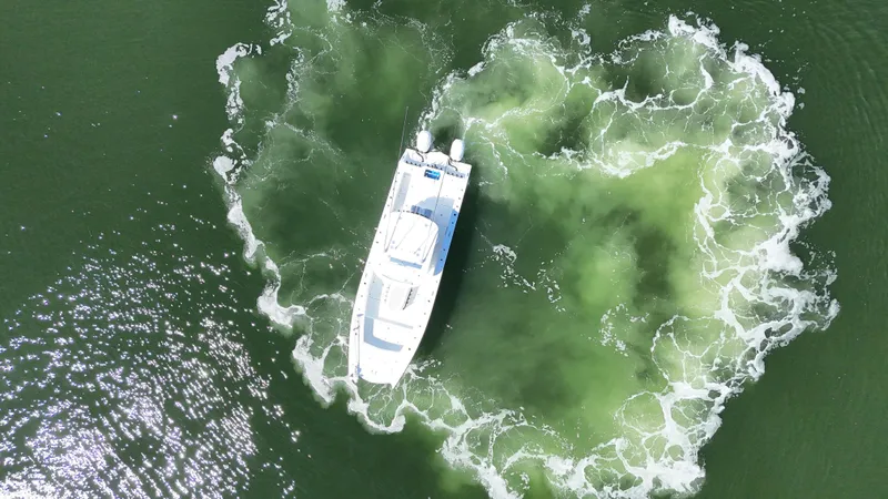 Slide: The Image of Aerial view of 2022 Freeman 34VH boat creating circular wake in green water. - 26