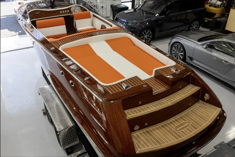 Slide: The Image of 2025 Comitti Venezia V28 luxury boat with orange and white seating in a showroom. - 11