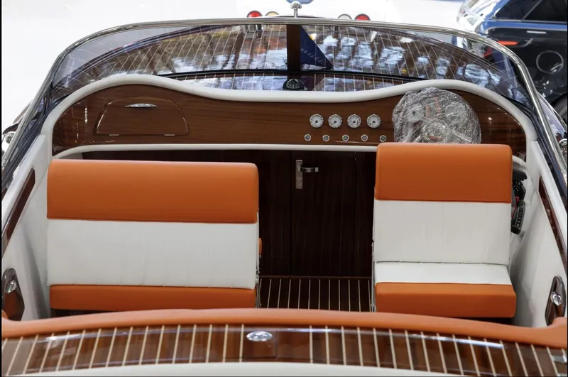 Slide: The Image of 2025 Comitti Venezia V28 boat interior with orange and white seating, wooden dashboard, and gauges. - 15