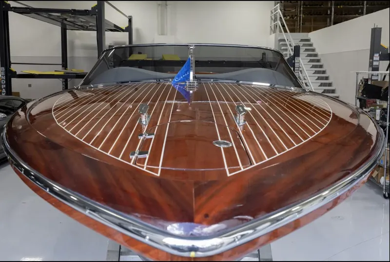 Slide: The Image of 2025 Comitti Venezia V28 luxury boat with sleek wooden deck in a modern showroom. - 2