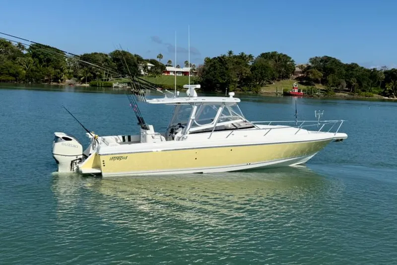 Slide: The Image of 2003 Intrepid 348 WA boat on calm water, featuring a yellow and white exterior. - 0