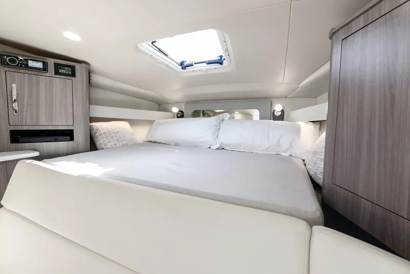 Slide: The Image of 2020 Regal 35 Sport Coupe cabin interior with bed, skylight, and modern wood cabinetry. - 25