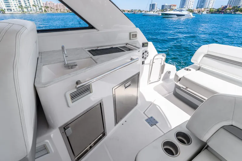Slide: The Image of 2020 Regal 35 Sport Coupe yacht interior with kitchenette and seating, overlooking water. - 30