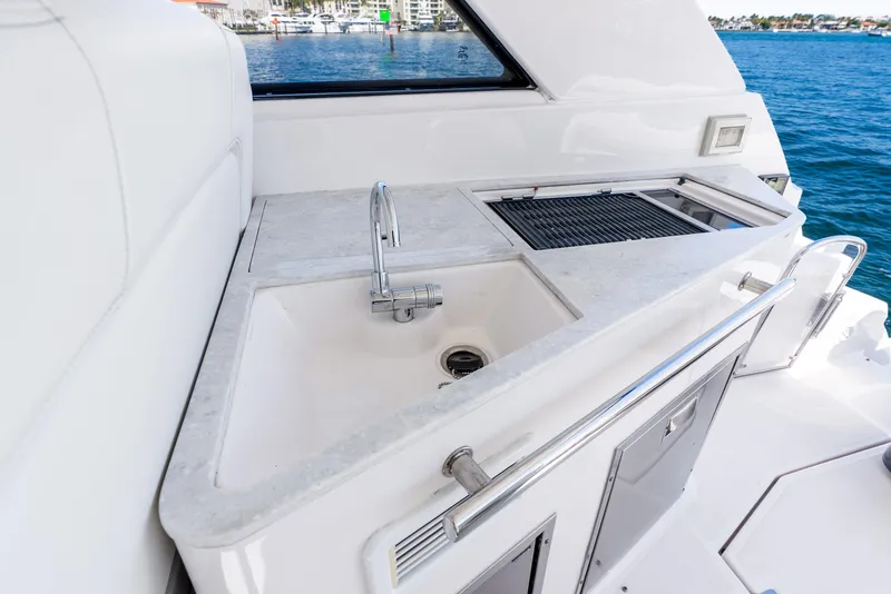 Slide: The Image of 2020 Regal 35 Sport Coupe yacht kitchenette with sink and grill, overlooking water. - 32