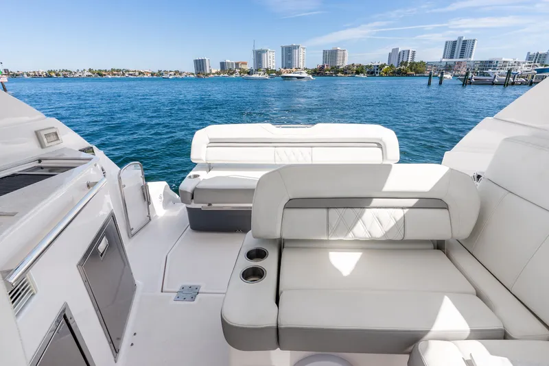 Slide: The Image of 2020 Regal 35 Sport Coupe yacht interior with white seating, overlooking a coastal cityscape. - 33