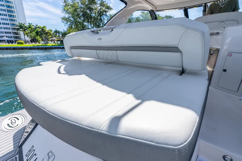 Slide: The Image of 2020 Regal 35 Sport Coupe boat with luxurious white seating and scenic waterfront view. - 34