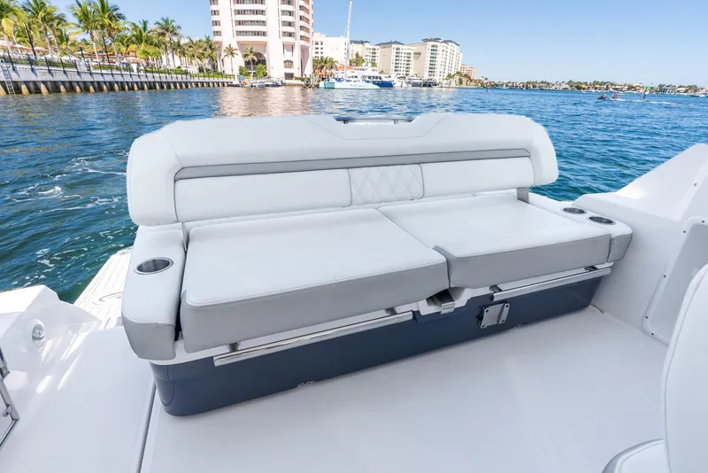 Slide: The Image of 2020 Regal 35 Sport Coupe boat interior with white seating, ocean view, and coastal buildings. - 35