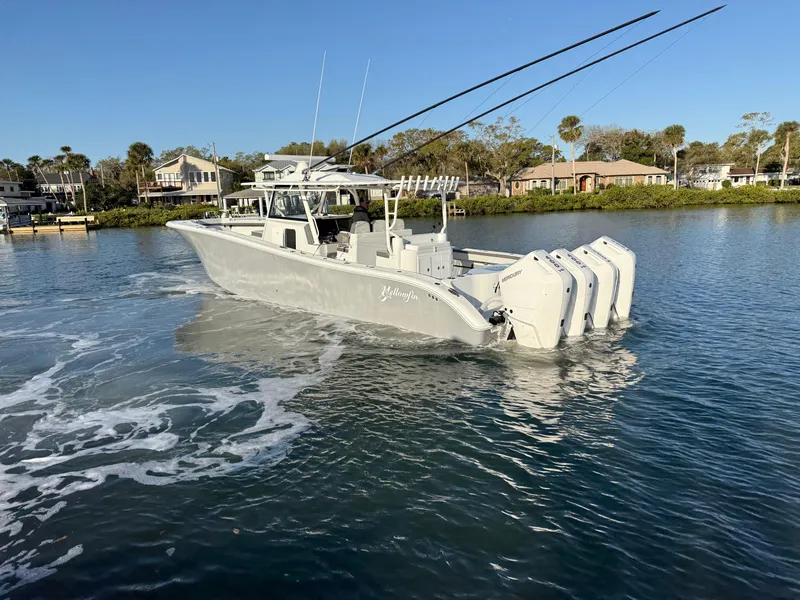 Slide: The Image of 2025 Yellowfin 42 CC boat cruising on a calm waterway near residential area. - 1