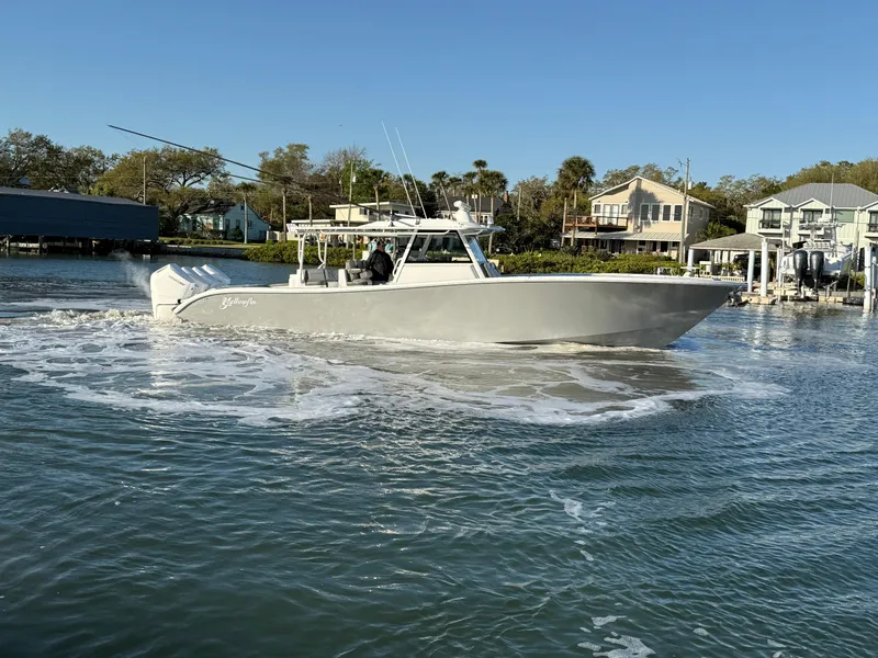 Slide: The Image of 2025 Yellowfin 42 CC boat cruising on a calm waterway near waterfront homes. - 2