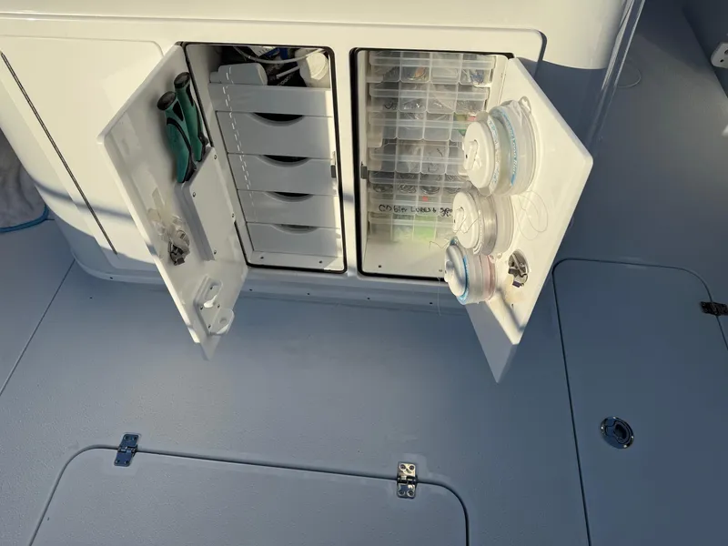 Slide: The Image of 2025 Yellowfin 42 CC boat storage compartments with open doors and organized fishing gear. - 22
