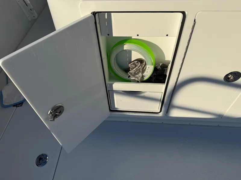 Slide: The Image of Open storage compartment on 2025 Yellowfin 42 CC boat, containing coiled green hose. - 23