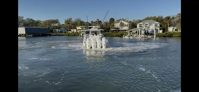 Slide: The Image of 2025 Yellowfin 42 CC boat navigating a calm waterfront near houses. - 3