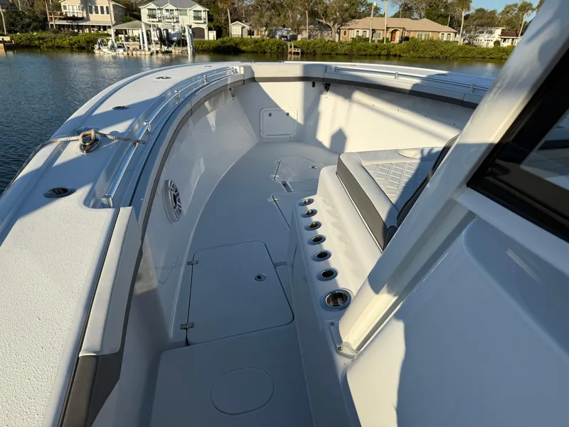Slide: The Image of 2025 Yellowfin 42 CC boat deck with seating and rod holders, docked by waterfront homes. - 51