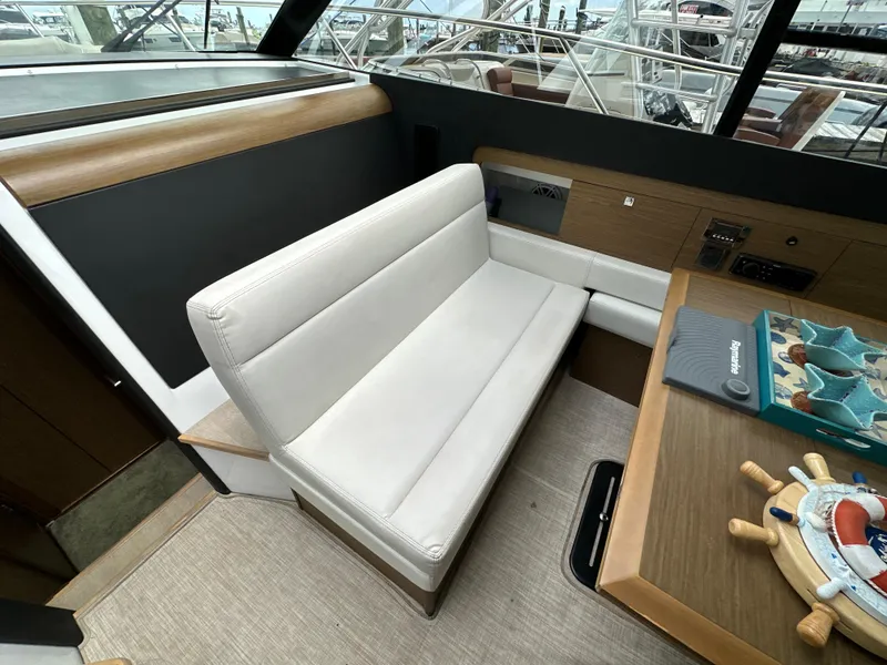 Slide: The Image of Interior of 2017 Jeanneau NC 11 boat with white seating and wooden table. - 49