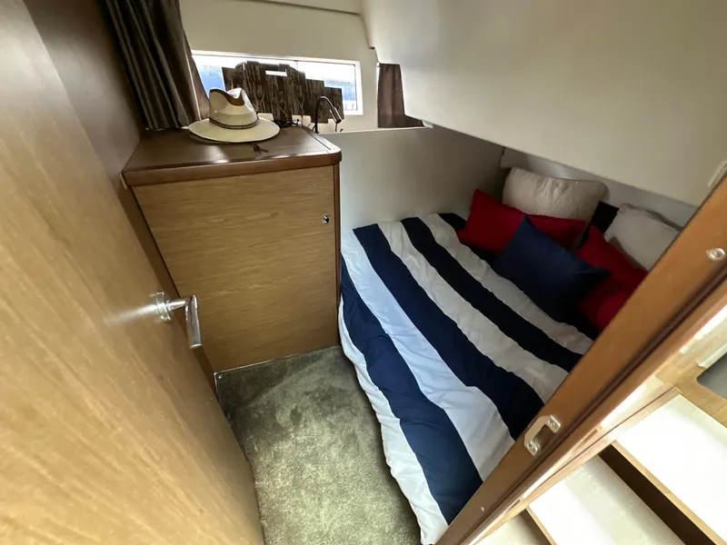 Slide: The Image of 2017 Jeanneau NC 11 cabin with striped bedding and wooden cabinetry. - 5