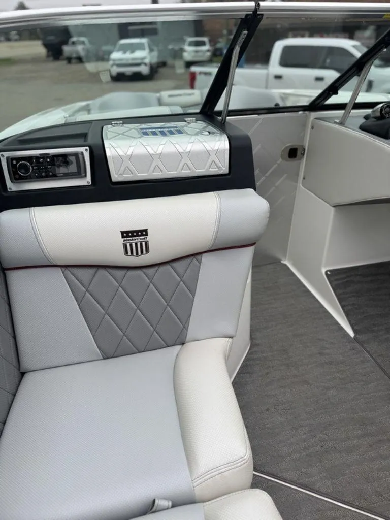 Slide: The Image of 2015 MasterCraft X46 boat interior with gray and white seating, dashboard, and open door. - 12