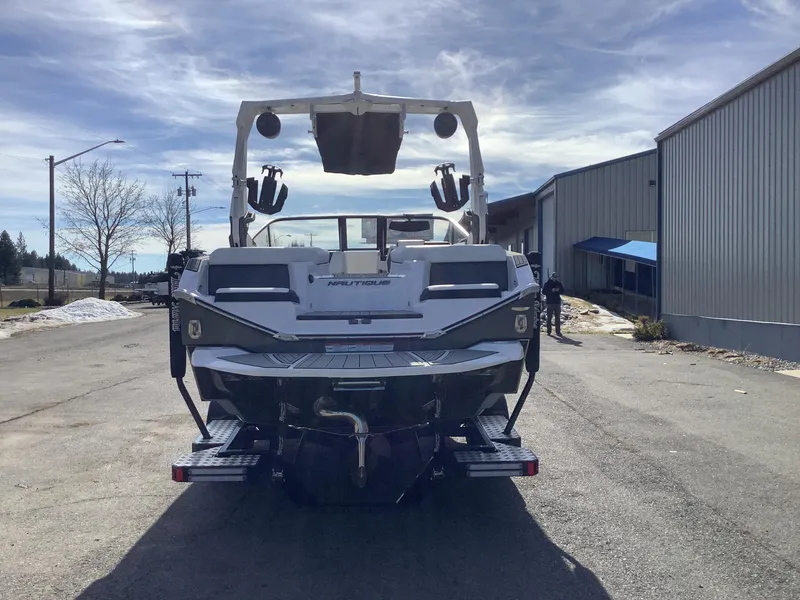 Slide: The Image of 2023 Nautique G21 boat parked outdoors, rear view, under a clear sky. - 3