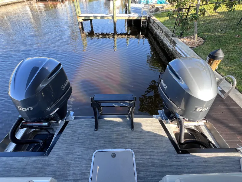 Slide: The Image of 2021 Bennington QX 27 pontoon boat with dual Yamaha 300hp engines docked by the water. - 11