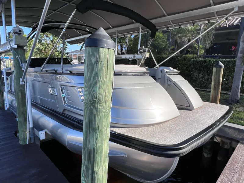 Slide: The Image of 2021 Bennington QX 27 pontoon boat docked, featuring a sleek design and spacious deck. - 5