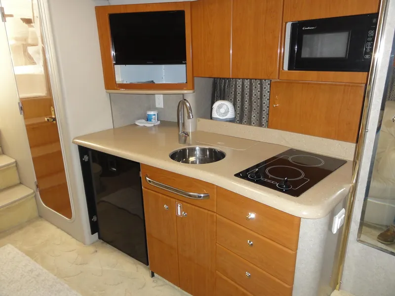 Slide: The Image of 2004 Formula 37 PC yacht kitchen with wood cabinets, sink, stove, microwave, and mini fridge. - 29