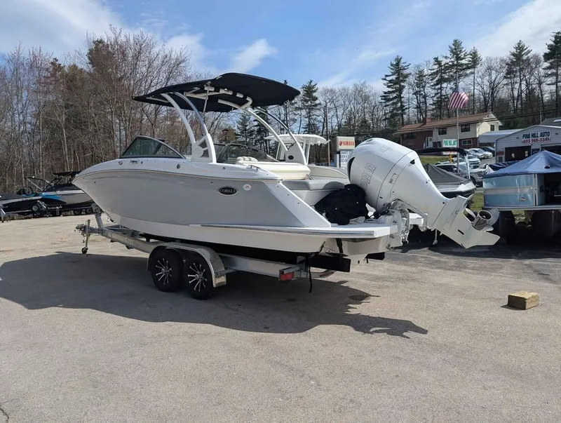 Slide: The Image of 2020 Cobalt 25SC boat on trailer, parked outdoors, with trees and buildings in background. - 2