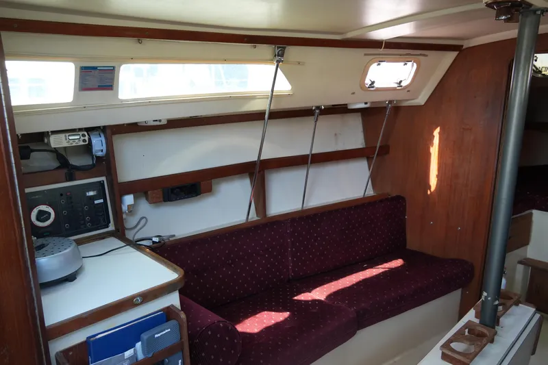Slide: The Image of Interior of a 1990 Catalina 28 sailboat with maroon seating and wooden accents. - 13