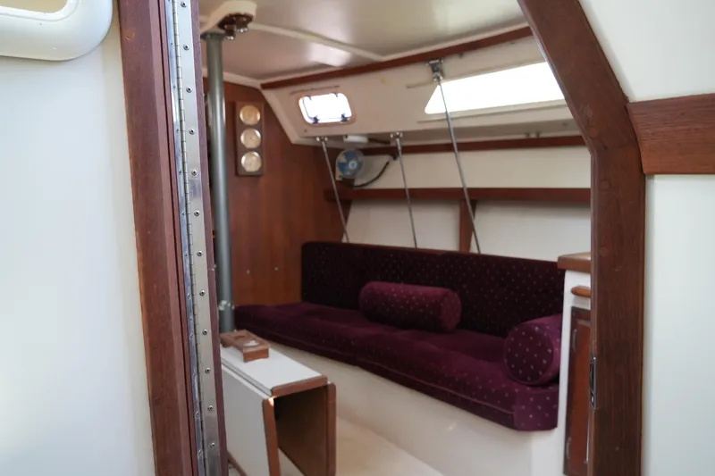 Slide: The Image of Interior of a 1990 Catalina 28 sailboat with maroon seating and wooden accents. - 19