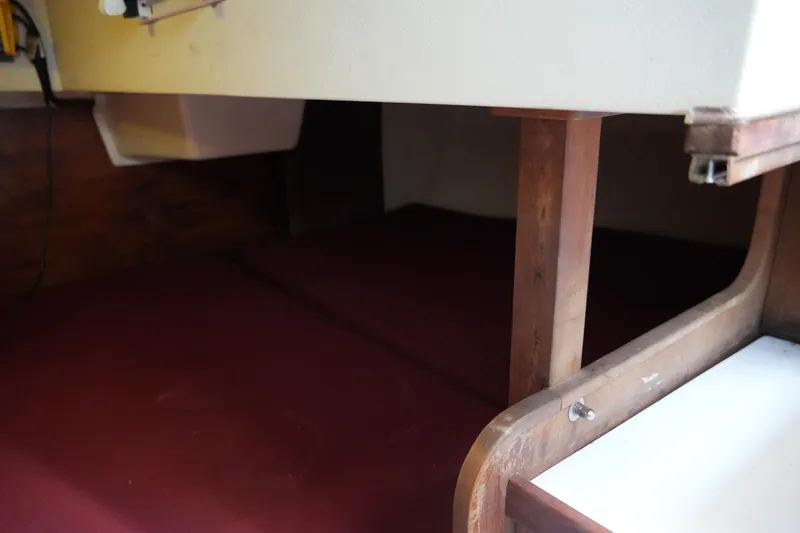 Slide: The Image of Interior cabin view of a 1990 Catalina 28 sailboat with wooden supports and maroon cushions. - 21