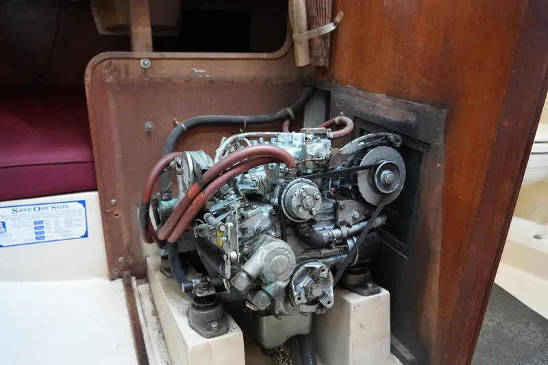 Slide: The Image of Engine compartment of a 1990 Catalina 28 sailboat, showcasing mechanical components and wooden interior. - 23