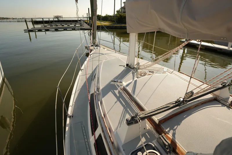 Slide: The Image of 1990 Catalina 28 sailboat docked in calm marina waters, showcasing deck and rigging. - 5