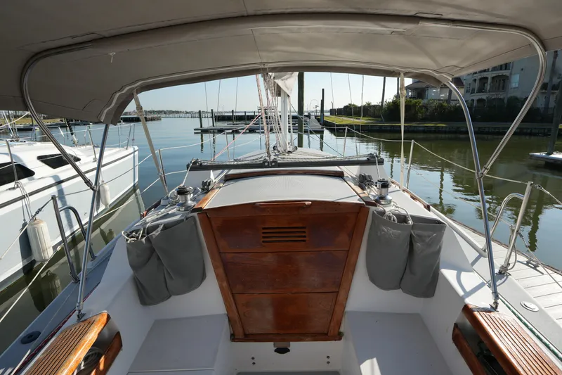 Slide: The Image of 1990 Catalina 28 sailboat cockpit with wooden accents, docked in a serene marina. - 7