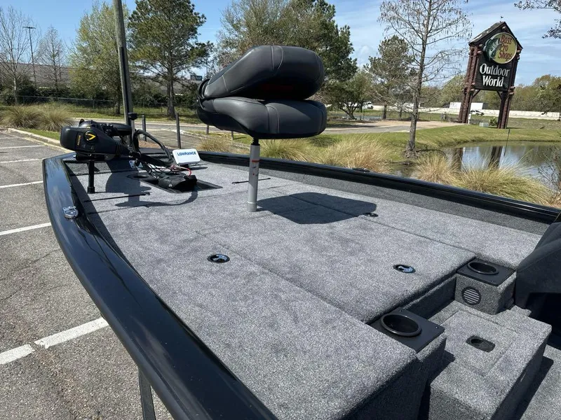 Slide: The Image of 2025 Tracker Pro Team 190 boat with gray deck and seating, parked near Outdoor World. - 4