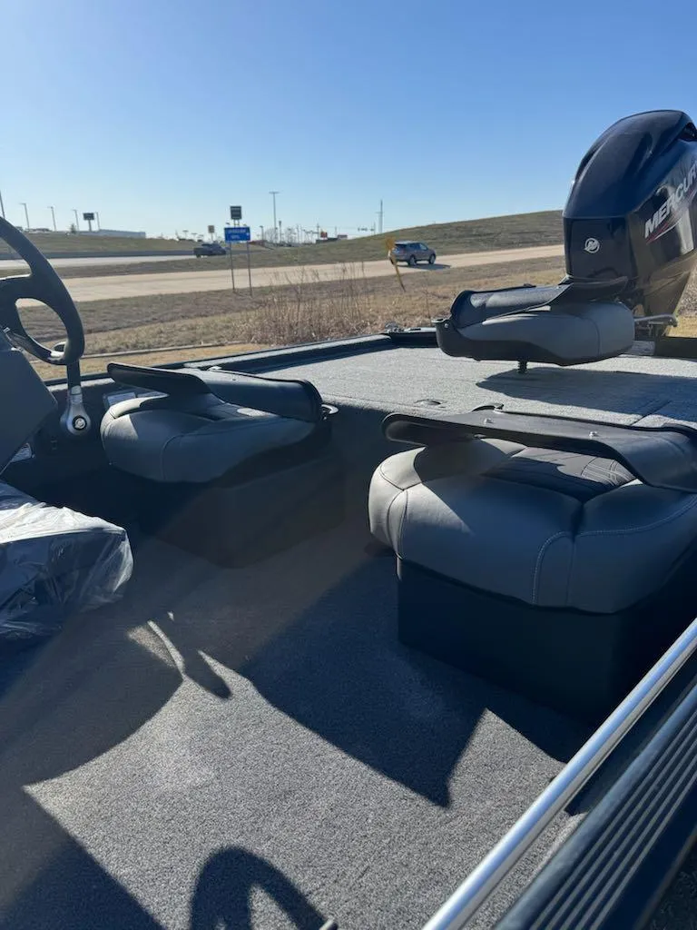 Slide: The Image of 2025 Tracker Bass Tracker Classic XL interior with seating and motor, under clear blue sky. - 9