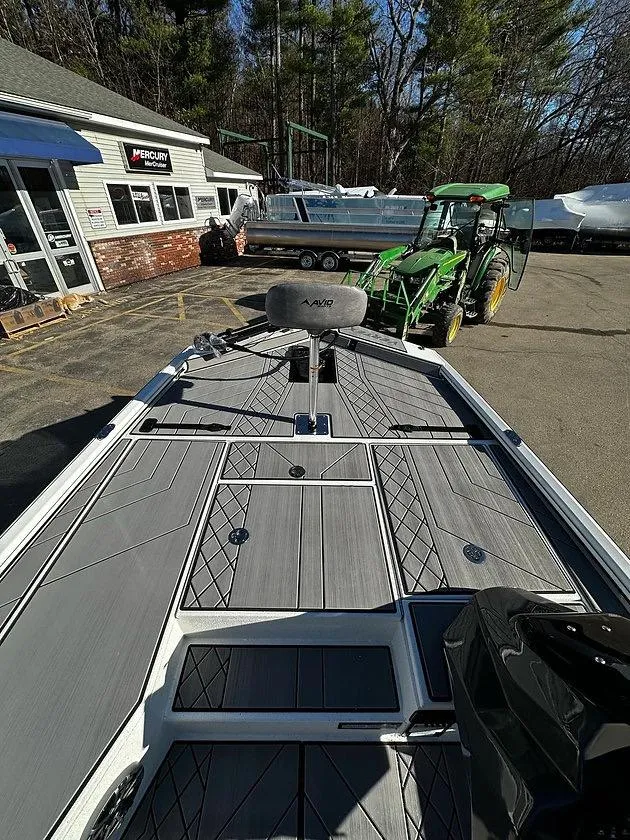 Slide: The Image of 2025 Avid 18 Vertex boat on display, parked near a tractor outside a dealership. - 5
