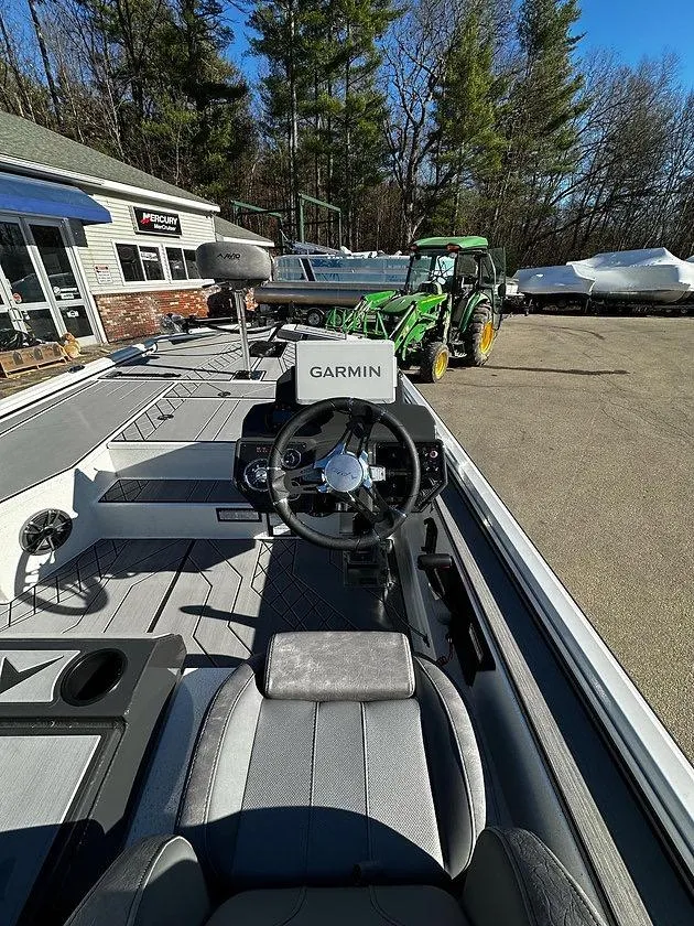 Slide: The Image of 2025 Avid 18 Vertex boat with Garmin navigation, parked near a tractor and building. - 6