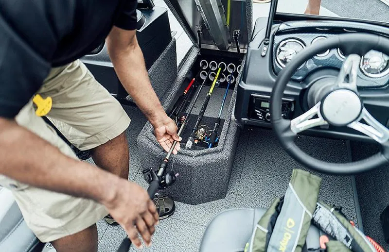 Slide: The Image of Man organizing fishing rods in 2025 Lowe FM 1775 WT boat storage compartment. - 2