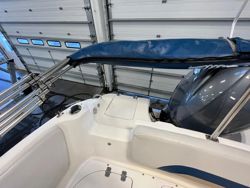 Slide: The Image of 2005 Godfrey FD211 boat interior with blue canopy and white seating in a garage. - 33