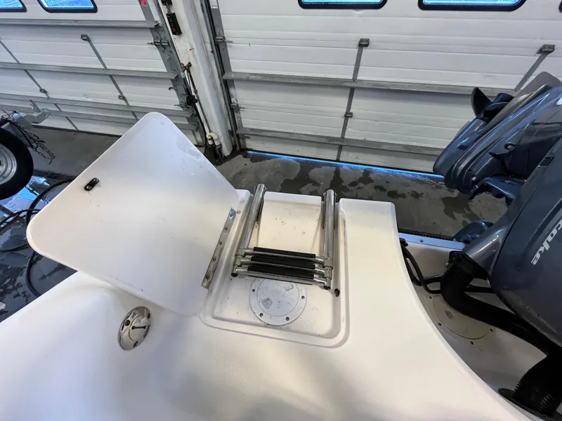 Slide: The Image of 2005 Godfrey FD211 boat with folded ladder and motor in a garage setting. - 34