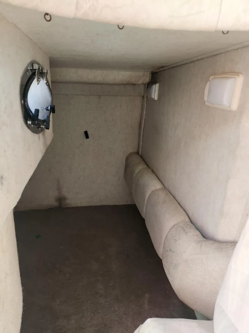 Slide: The Image of 2001 Sea Ray 240 Sundancer cabin interior with beige upholstery and porthole window. - 12